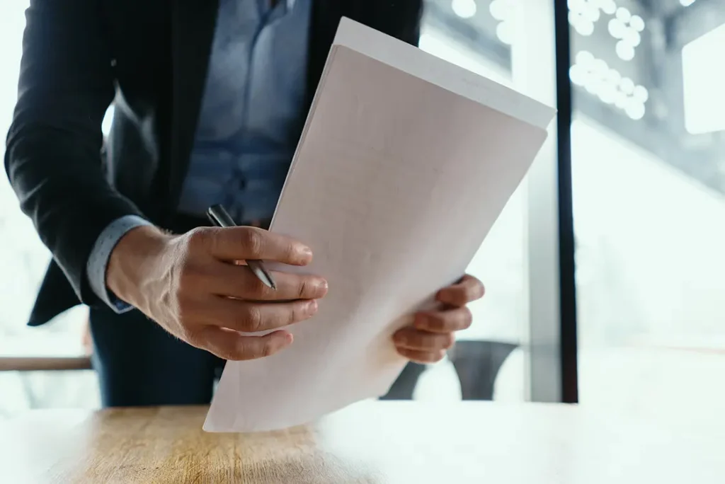 Homem de terno segurando papéis sobre uma mesa