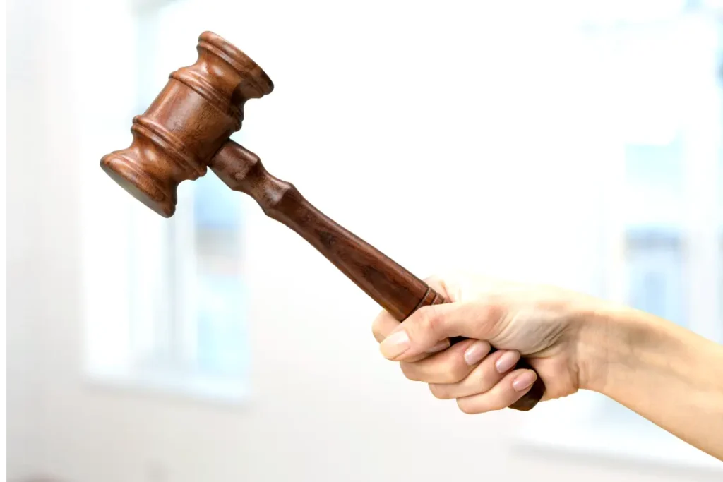 Mão de mulher branca segurando um martelo de tribunal