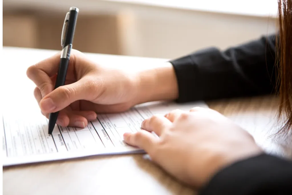 Mãos femininas assinando documento